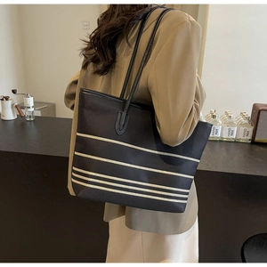 Detail of minimalist black canvas tote bag with horizontal stripes and long leather straps