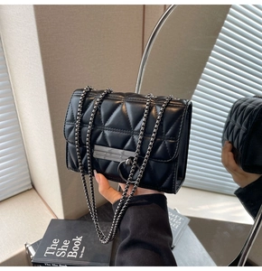Detail of black quilted leather shoulder bag with metallic clasp and chain strap