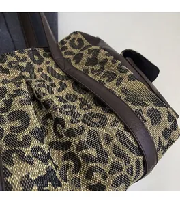 Detailed macro view of woven leopard print fabric and brown leather handle stitching