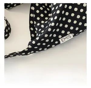 Close-up of black and white polka dot fabric tote bag with a white EMIS brand label tag