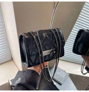 Detail of black quilted leather shoulder bag with chain strap and metallic buckle