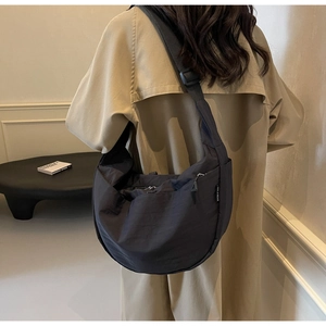 Detail showing high-capacity black nylon half-moon crossbody bag with woven strap