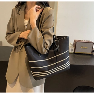 Detail of a large black canvas tote bag with white stripes styled in a lifestyle scene