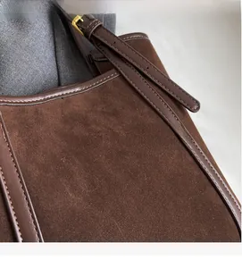 Detailed close-up of brown suede and leather stitching with adjustable metal buckle strap