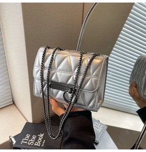 Close-up of silver quilted chain bag featuring black metal hardware and ring clasp