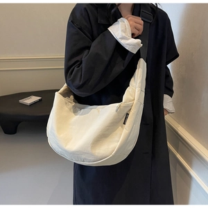 Detail of minimalist beige crescent bag with adjustable wide black shoulder strap