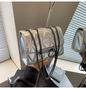 Detailed macro of silver metallic quilted handbag with chain strap and triangle pattern