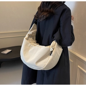 Close-up of off-white canvas crescent bag featuring a unique white triangular zipper pull