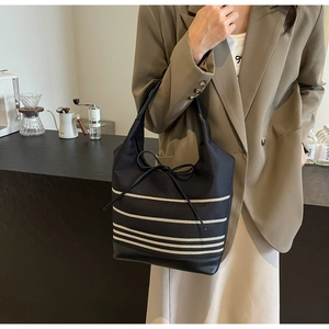 Detail of black striped canvas tote bag with bow design and leather bottom reinforcement