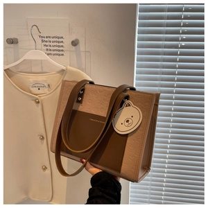Detail der geprägten Shopper-Tasche mit Bärenanhänger und modischem Muster