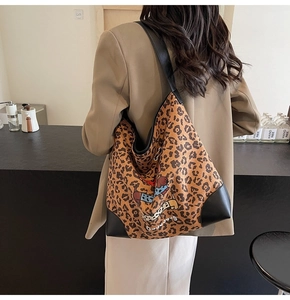 Detailed view of large leopard print tote bag with dog illustration on model's shoulder