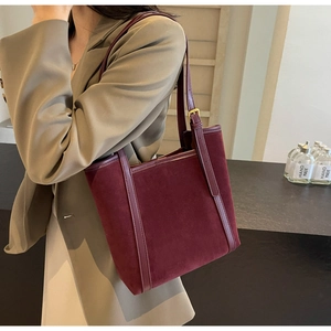 Close-up of deep red suede tote bag featuring adjustable shoulder strap and gold buckle