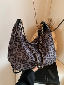 Graue Hobo-Tasche mit Leopardenmuster und goldener Kette in einer stilvollen Lifestyle-Szene