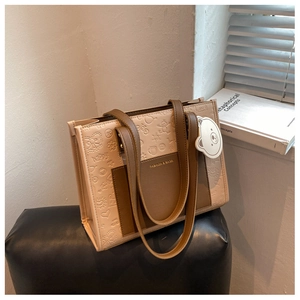 Detail der geprägten Shopper-Tasche mit Cartoon-Mustern und süßem Bär-Anhänger