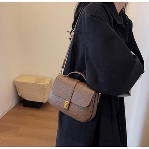 Detail of brown litchi pattern leather bag with golden rotary lock and fine craftsmanship