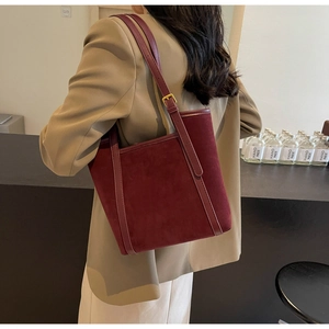 Detail of burgundy suede tote bag with slim shoulder straps and gold metal buckles