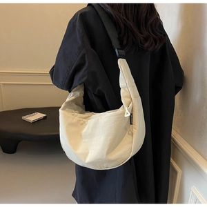 Model view showing the cream crescent crossbody bag with adjustable wide black strap