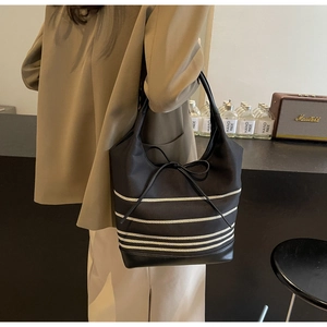 Detail of black striped canvas tote bag with leather拼接and bow decoration