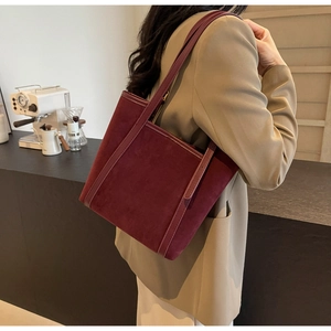 Detail view of burgundy suede tote bag styled with a professional blazer for women