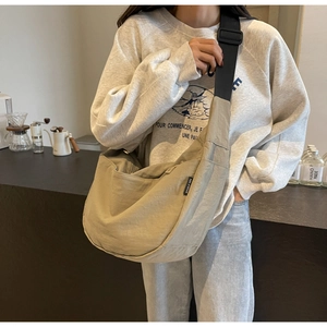 Detail of khaki nylon dumpling bag featuring a wide adjustable strap and brand tag