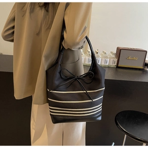 Detailed view of striped canvas tote bag with bow detail and leather trim for women