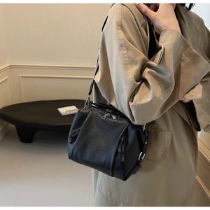 Detail of black lychee grain leather crossbody bag with silver double zippers