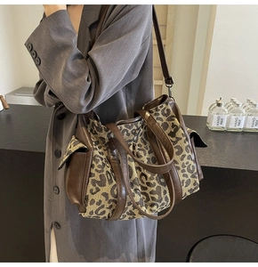 Detail of vintage leopard print tote bag with brown leather accents on a female model