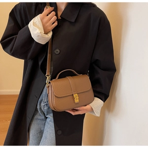 Detail of vintage brown saddle bag showing litchi grain texture and gold swivel lock