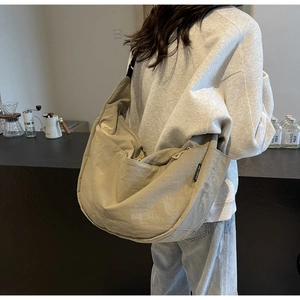 Detail of khaki nylon crossbody bag with drawstring side pocket and wide strap