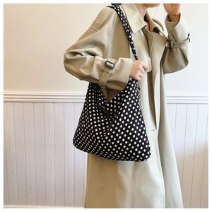 Detail shot of the EMIS woven logo tag on a black and white polka dot canvas tote bag