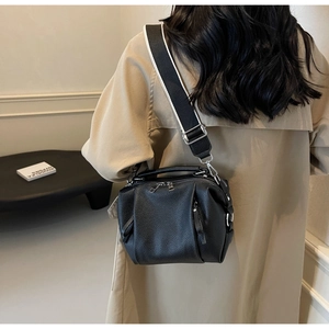 Detail of black pebbled leather crossbody bag with wide black and white textile strap