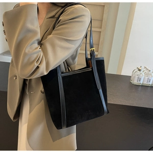 Close-up of adjustable strap and golden buckle on a black suede tote bag