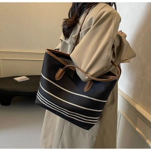 Detail of striped canvas tote bag with brown leather handles and reinforced edges