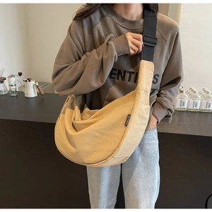 Detail of beige nylon crossbody bag with adjustable strap and brand label on side