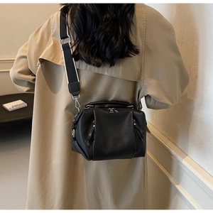 Detailed view of black textured pleated handbag with stylish black and white wide strap