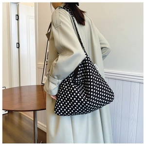 Macro detail of black canvas hobo bag with white polka dots and EMIS woven brand label