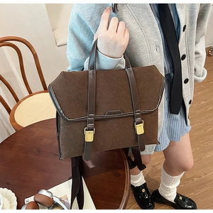 Detail eines matten braunen Rucksacks im Vintage-Stil mit Lederriemen und Goldschnallen