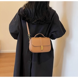 Brown litchi grain leather crossbody bag shown on a model with golden square twist lock