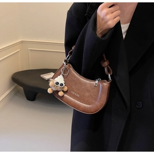 Detail der braunen Satteltasche im Vintage-Stil mit Bärenanhänger und Logo-Druck