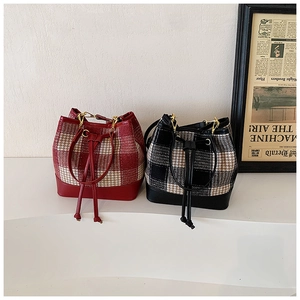 Détail de sacs seaux à carreaux rouges et noirs avec poignées en cuir et cordon serrage