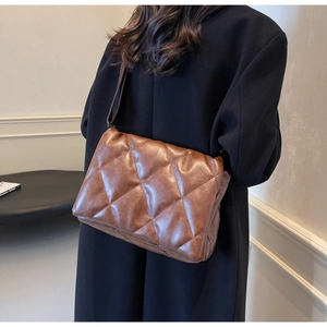 Detail of a brown quilted shoulder bag with large diamond stitching and PU leather texture
