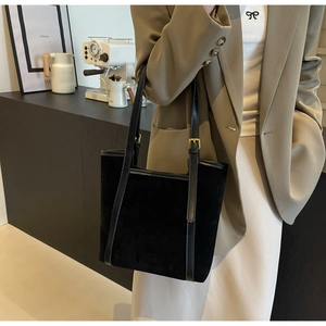 Detail of black suede tote bag with smooth leather trim and adjustable gold hardware