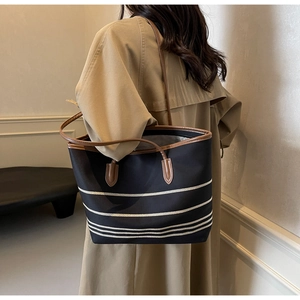 Lifestyle shot of large canvas tote with white stripes and brown leather straps on model