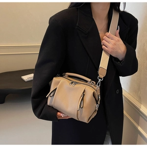 Detail of khaki pebbled leather pillow bag with wide woven strap and metal zipper