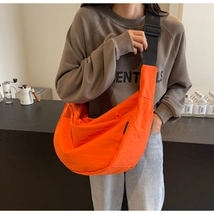 Close-up of bright orange crescent messenger bag with adjustable wide black shoulder strap