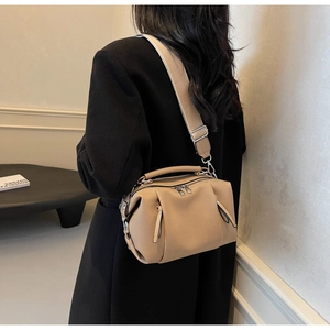 Khaki pebbled leather crossbody pillow bag with wide strap worn on a black wool coat