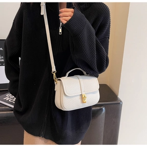 Detailed close-up of white lychee texture leather mini bag with gold metal twist lock