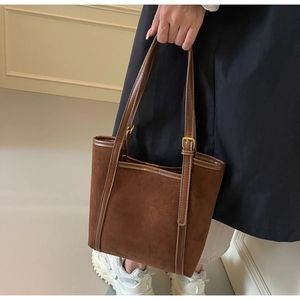 Macro detail of dark brown suede tote bag featuring premium gold metal adjustment buckles