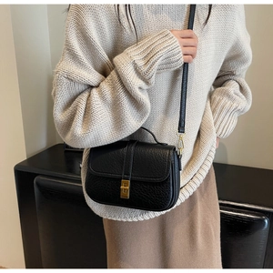 Close-up of black lychee grain leather crossbody bag with gold metal twist lock detail
