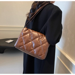 Close-up of brown quilted faux leather tote bag showing glossy texture and rhombic pattern